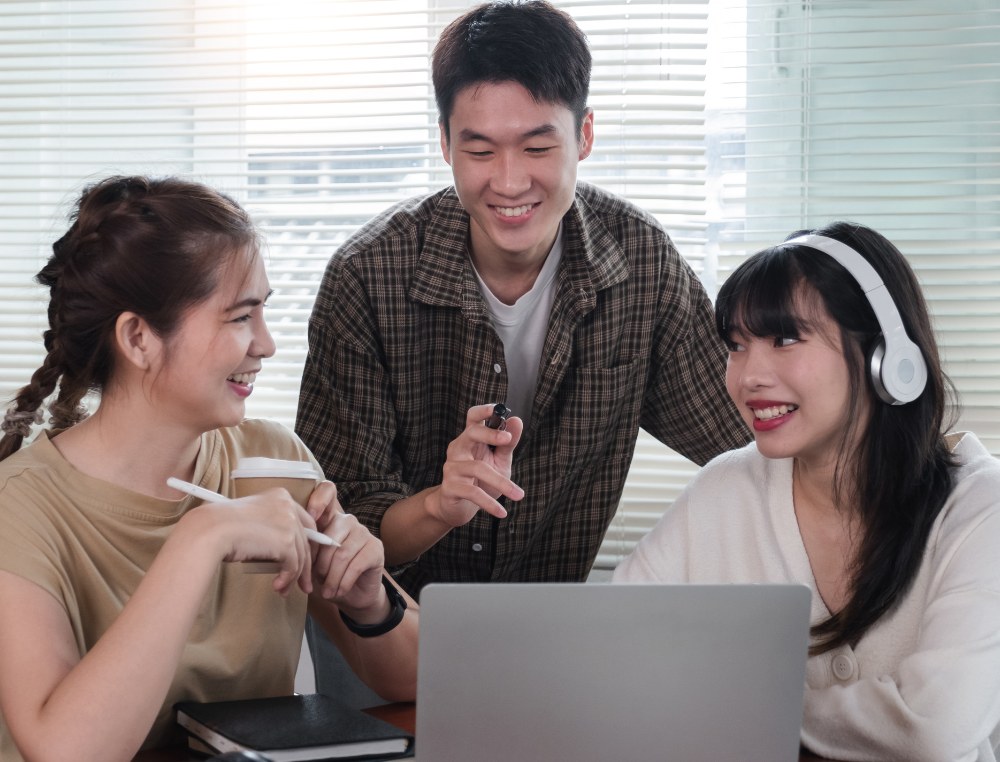 Three colleagues reviewing work on a laptop