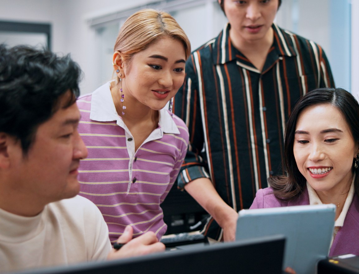 Colleagues gathered around a screen reviewing an account