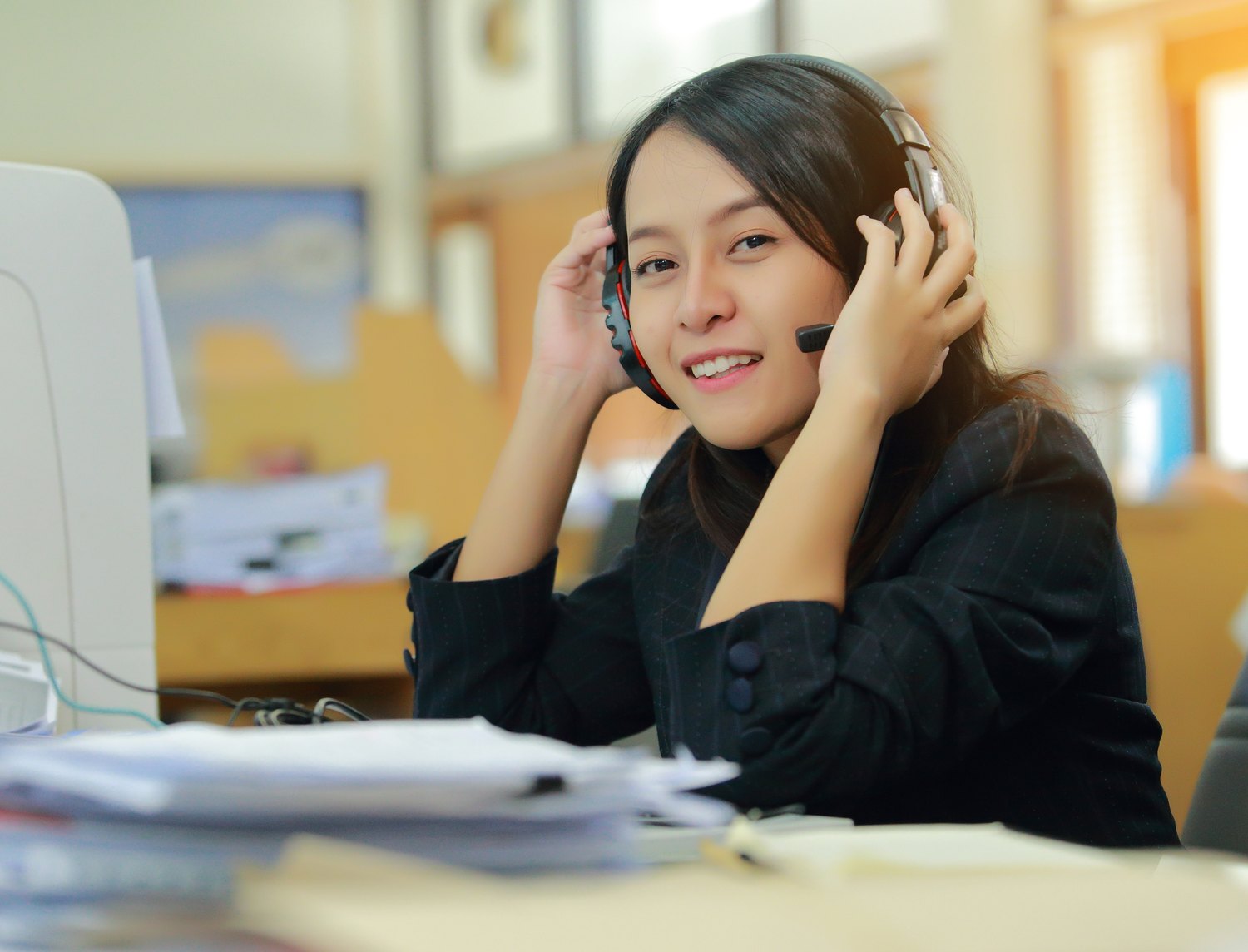 Agent adjusting her headset at her desk