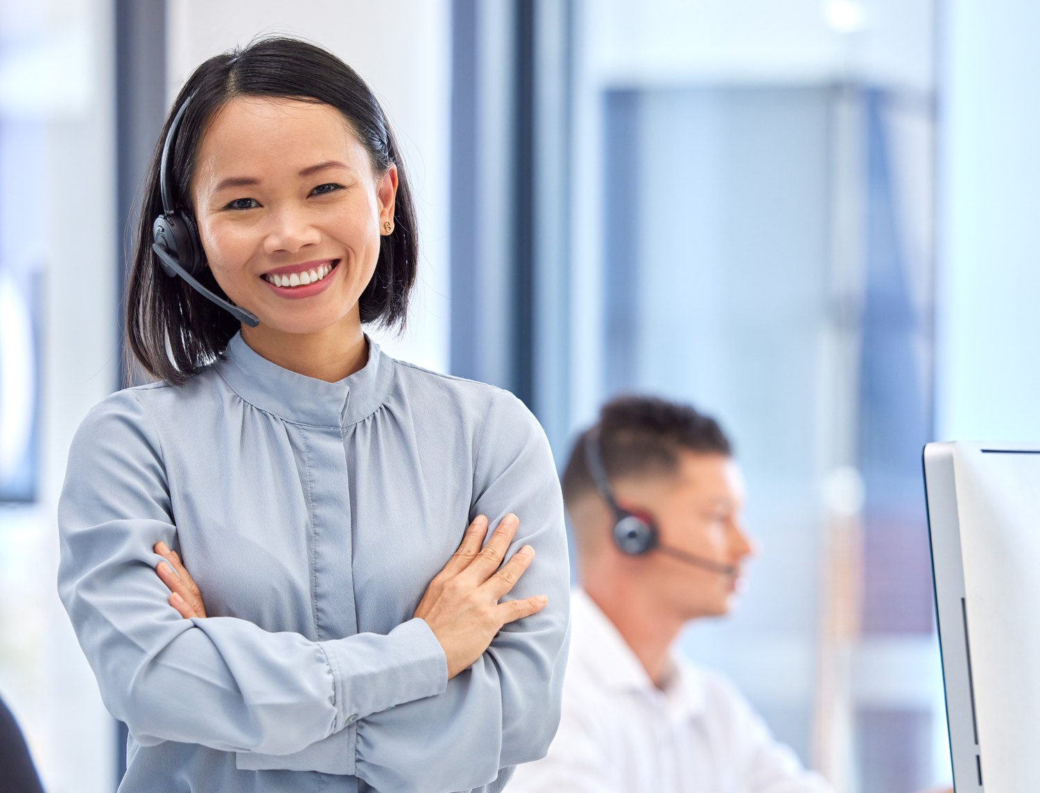 Agent standing on the support floor beside a colleague at his desk